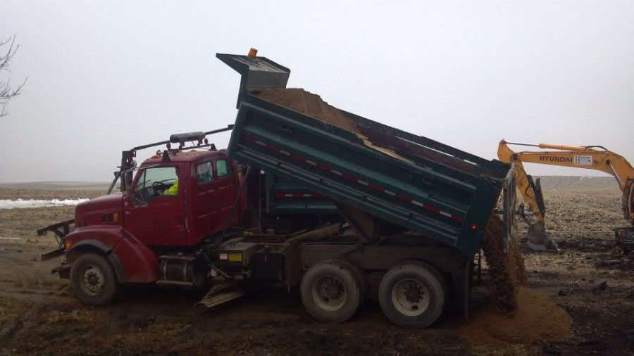Dump truck placing sand and dirt at a job site