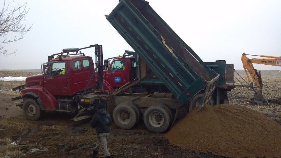 Dump trucks and excavator hauling and placing fill dirt